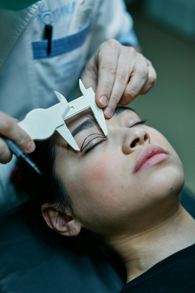 A surgeon measures a patient's eyelid for blepharoplasty preparations.
